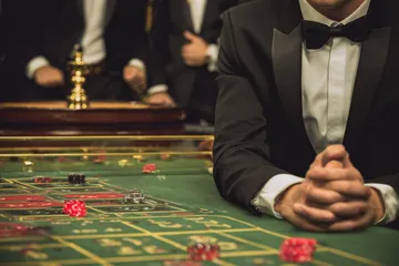 A professional dealer in a tuxedo greeting players at the roulette table, symbolizing the authentic live casino feel at 1111BED.